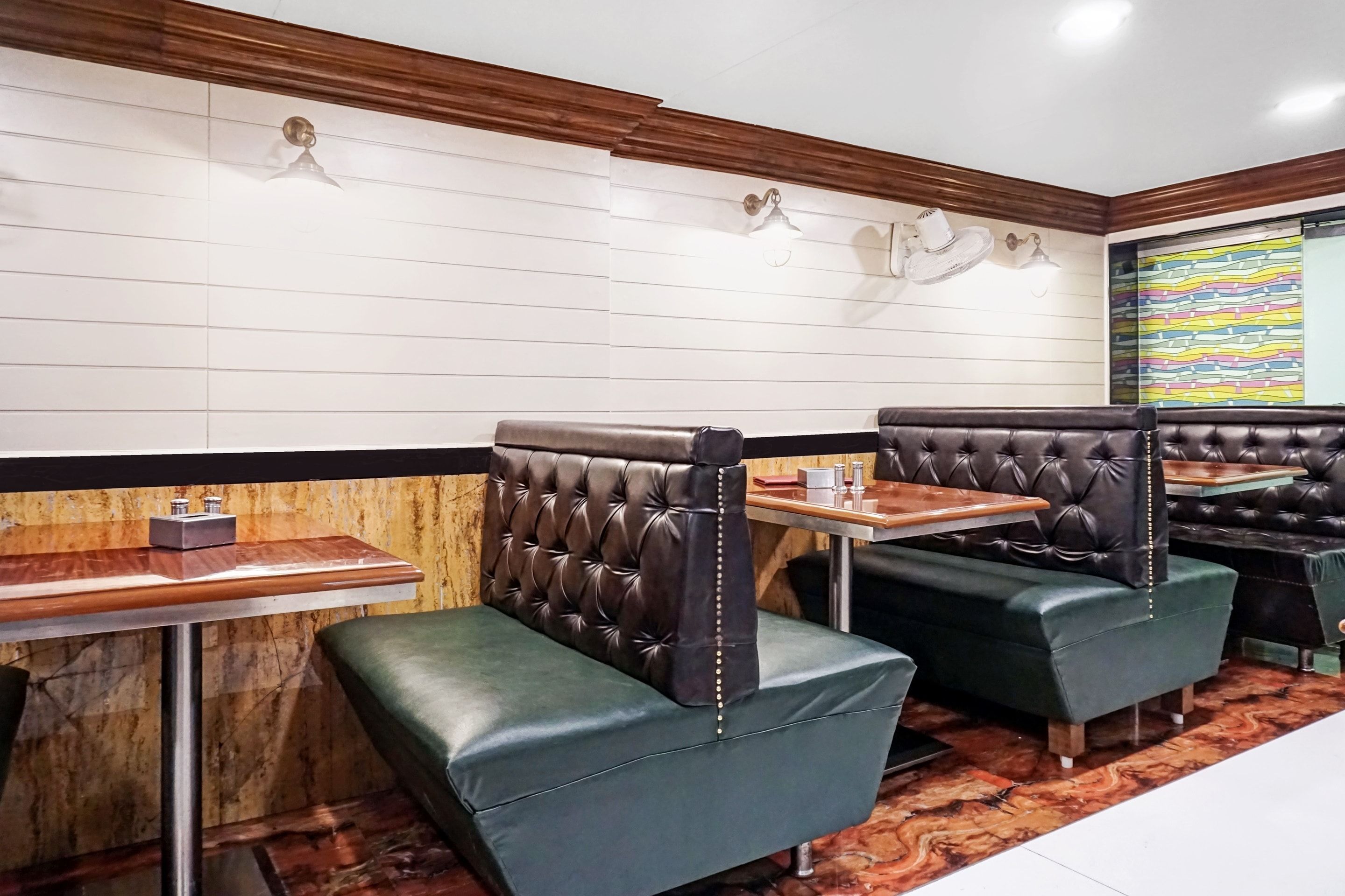 A restaurant interior with booth seating, wooden tables, and a patterned wall.