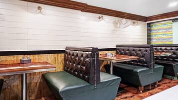 A restaurant interior with booth seating, wooden tables, and a patterned wall.