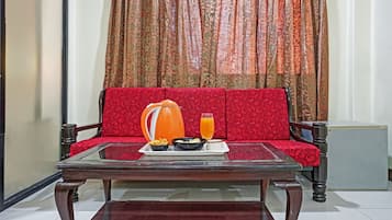 A room with a red sofa, a glass coffee table, and a small refrigerator.