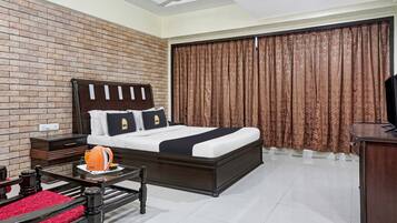 A hotel room with a brick-patterned wall, a bed with a dark headboard, a television on a wooden cabinet, and a coffee maker on a table.