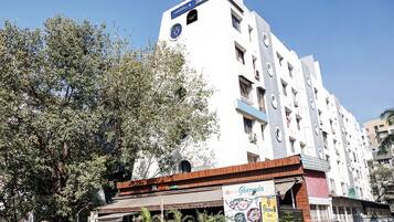 A multi-story building with a sign for 'Hotel Gharonda' and a 'Home Delivery Available' banner.
