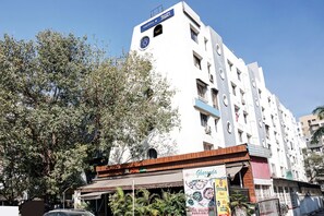 A multi-story building with a sign for 'Hotel Gharonda' and a 'Home Delivery Available' banner.