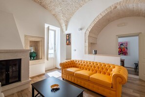 A living room with a fireplace, a yellow sofa, and an arched ceiling. - Roof-Top Maisonette | Old Town by TrulloVista (Martina Franca)