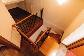 Eine Holztreppe mit schwarzen Geländern, die zu einer Empfangsebene mit einem Heizkörper führt.