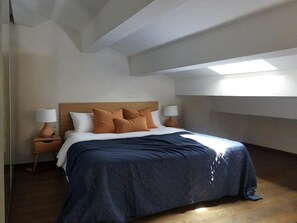 Ein Schlafzimmer mit einem Bett, zwei Nachttischen und einem Oberlicht.