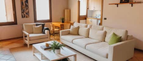 A living room with a sofa, coffee table, and chairs, a kitchen area, and a dining table.