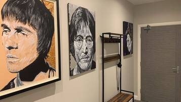 A hallway with framed artwork on the wall, a bunk bed, and a door.
