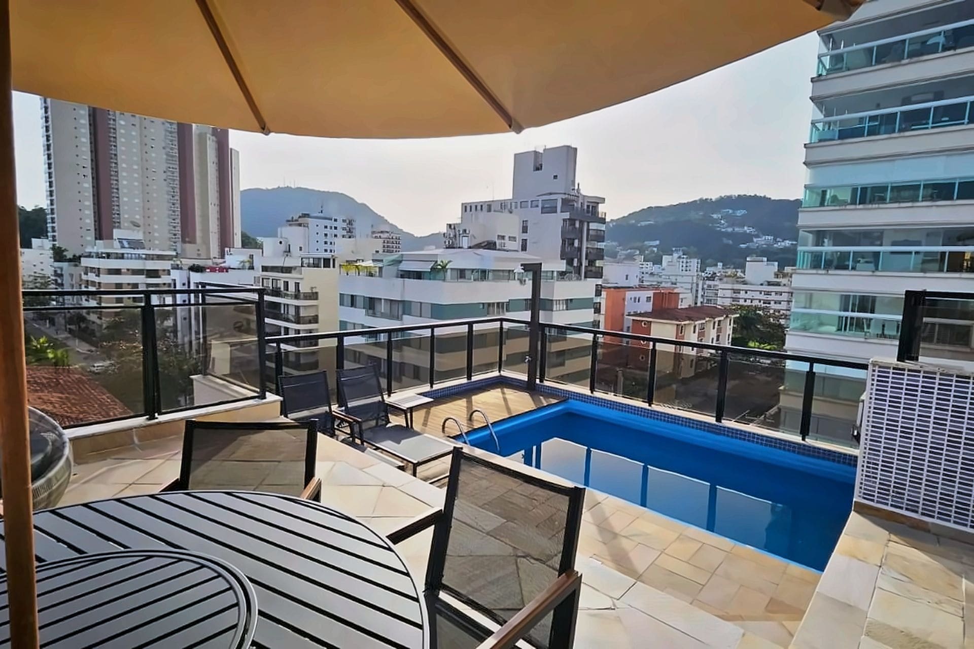 A balcony with a pool, outdoor furniture, and a view of the cityscape.