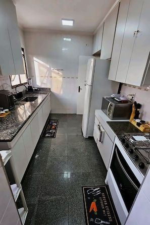 Eine kleine Küche mit Kühlschrank, Herd und Tischgeräten.