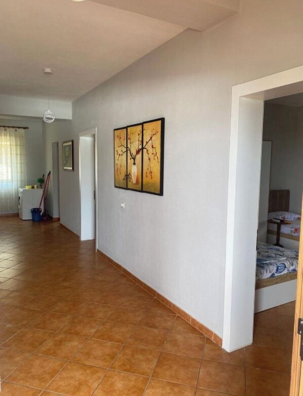 A spacious hallway with a tiled floor, a framed artwork on the wall, and a door leading to a bedroom. - “Marina View – Relax, Sea & Sunset in Shengjin” (Shëngjin)