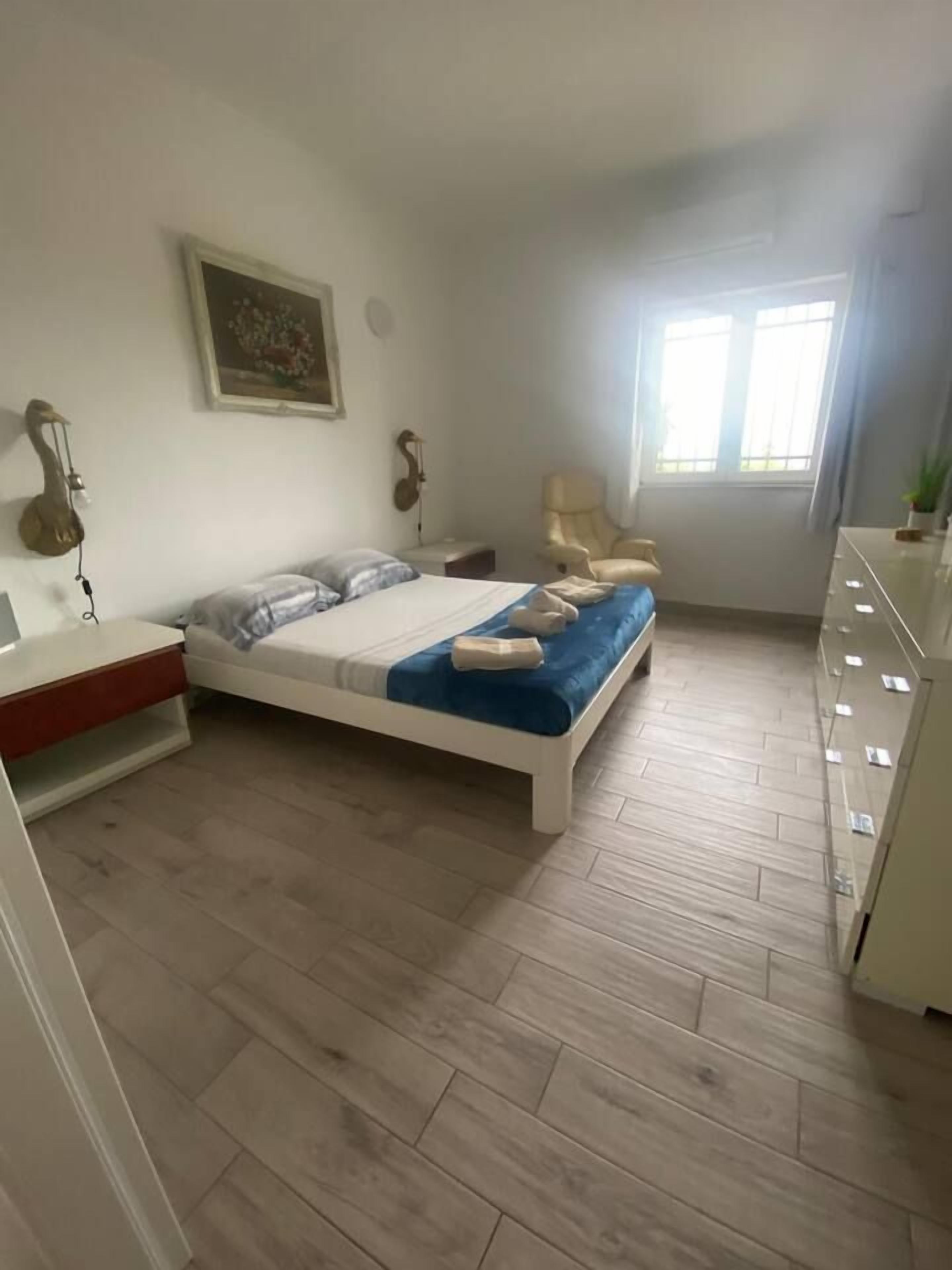 Een slaapkamer met een bed, een stoel, een bureau en een dressoir.
