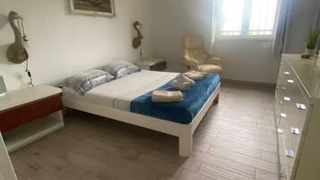 Een slaapkamer met een bed, een stoel, een bureau en een dressoir.