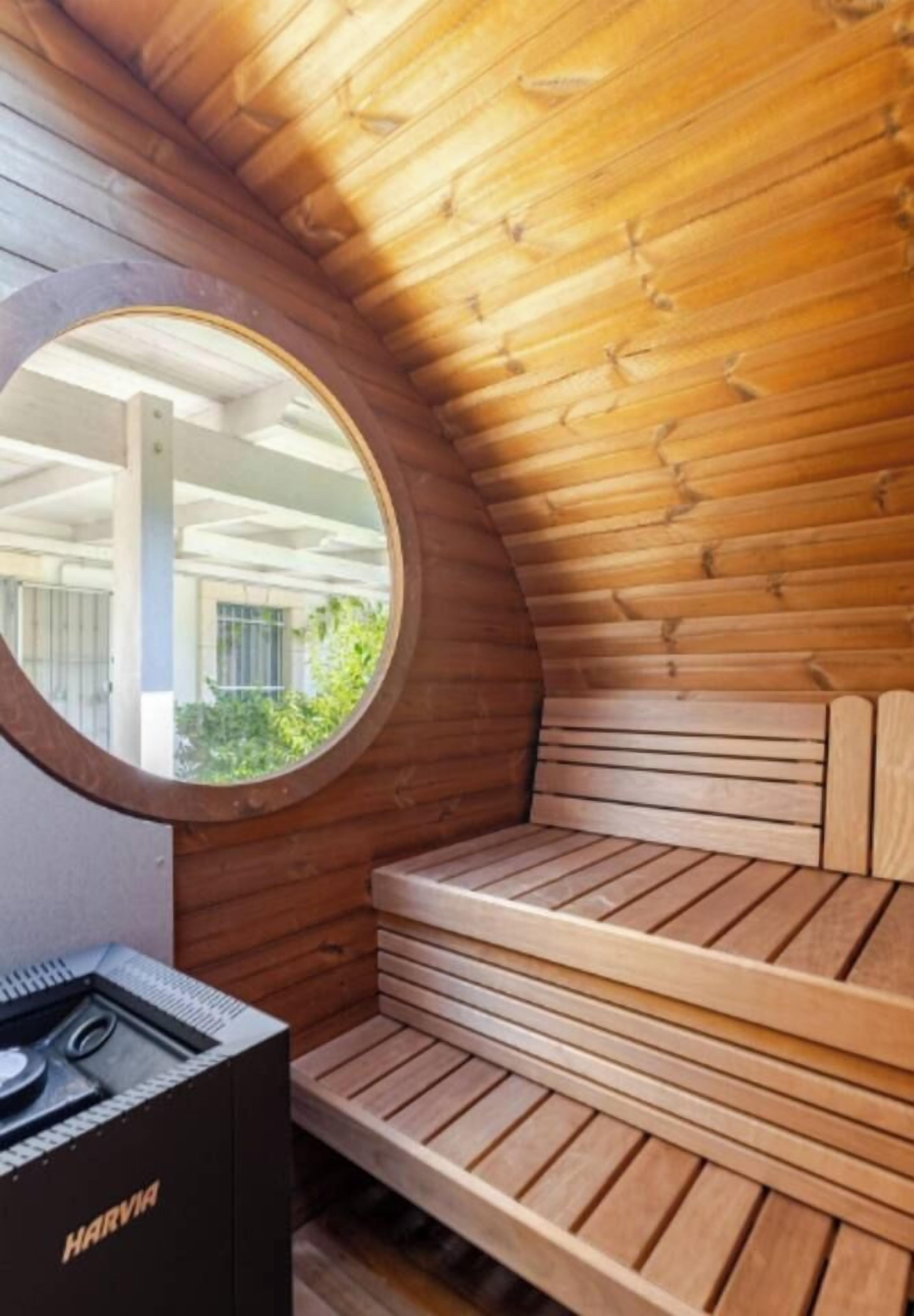Een sauna met houten banken en een rond raam.