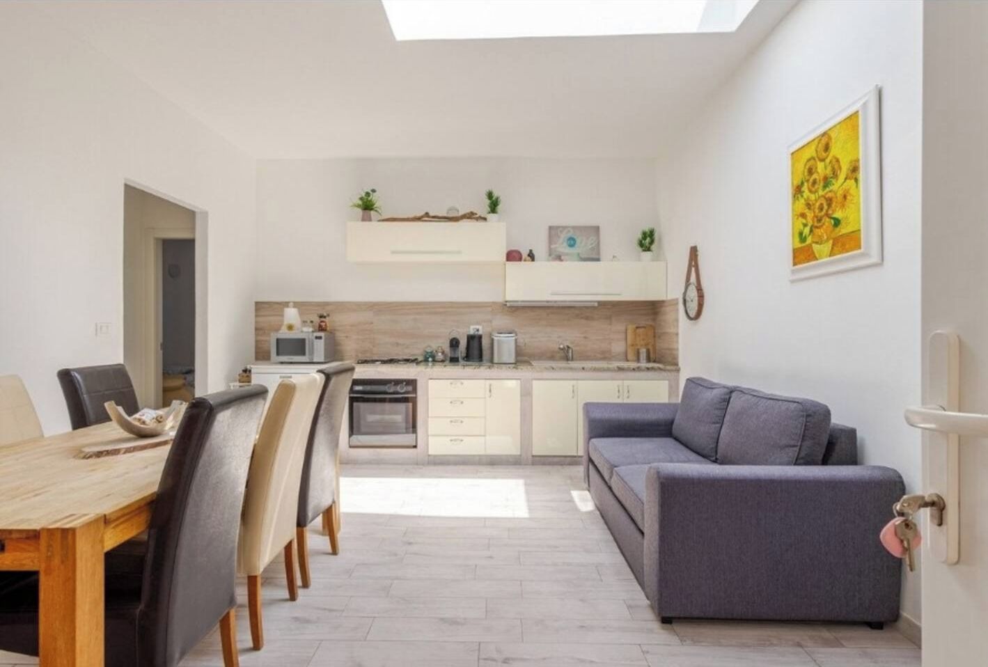 Bright open-plan studio with skylight, dining area, and cozy sofa