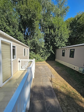 Casa móvel com varanda coberta e área de deck cercada.