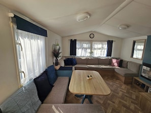 Uma sala de estar aconchegante com um sofá, um banco, uma mesa de madeira e uma televisão.