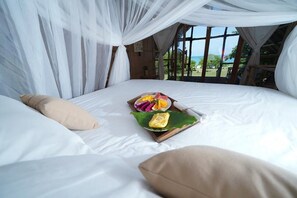 Ein Bett mit Baldachin, ein Tablett mit Speisen und Blick ins Freie.