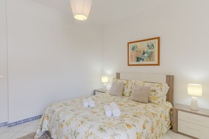 Ein Hotelzimmer mit einem Bett, zwei Nachttischen, einem Bild an der Wand und Handtüchern auf dem Bett.