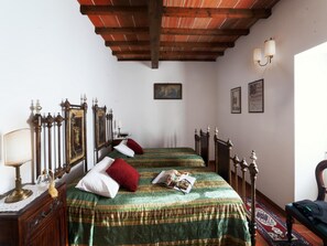 A room with two beds, a wooden ceiling, a nightstand with a lamp, and wall-mounted lights. - Accessible Tuscan Apt, Garden & Pool (Poppi)