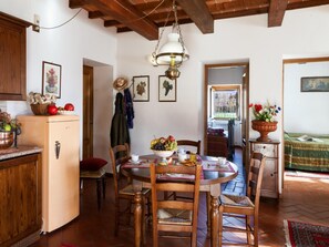 A rustic kitchen with a wooden ceiling, a refrigerator, and a dining table with chairs. - Accessible Tuscan Apt, Garden & Pool (Poppi)