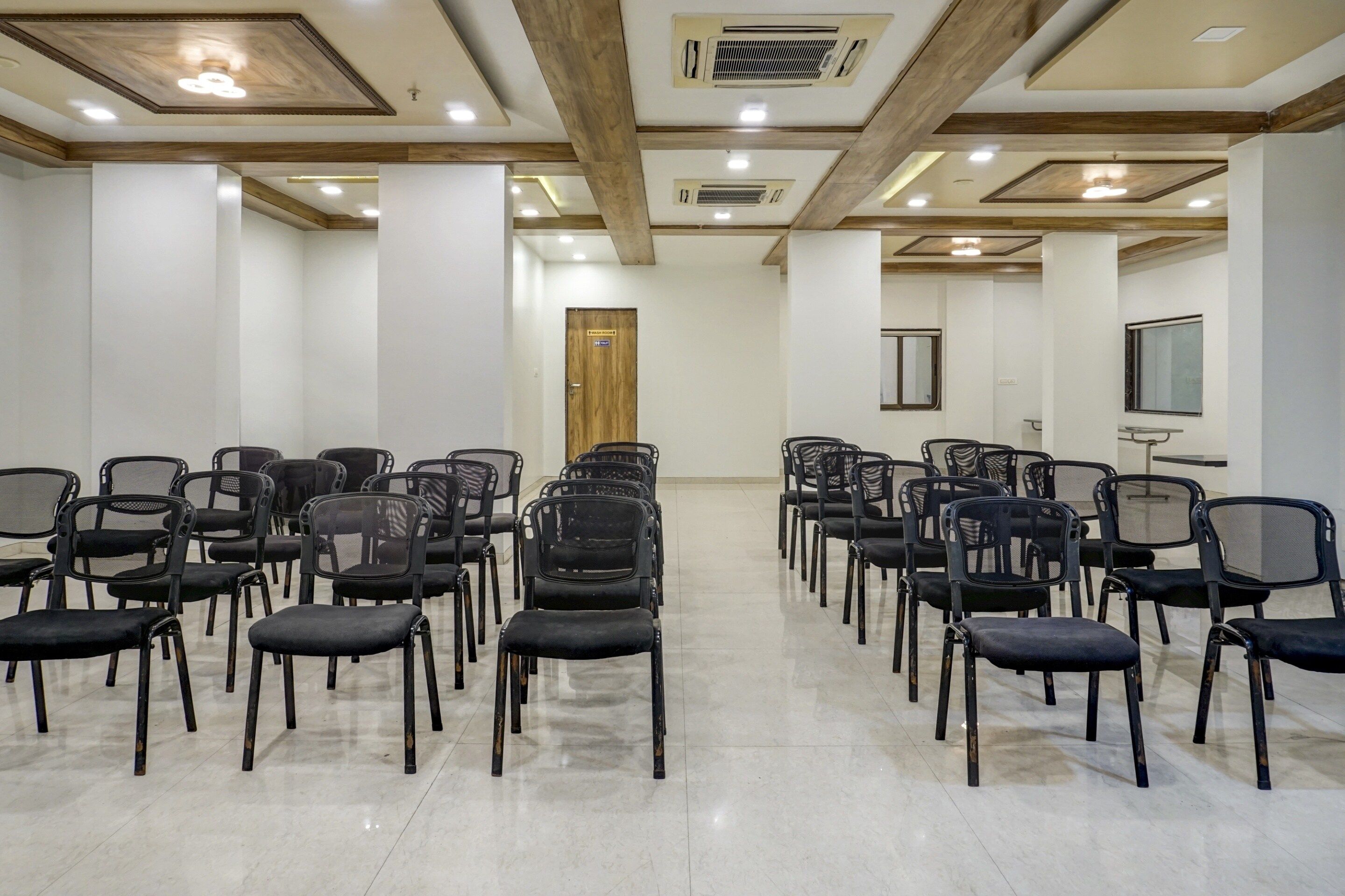 A conference room with rows of chairs, a wooden door, and a window.