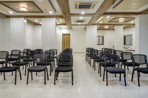 Un salón de conferencias con filas de sillas, una puerta de madera y un ventanal.