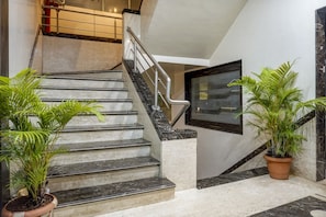 A staircase with marble steps and metal railings, flanked by potted plants.