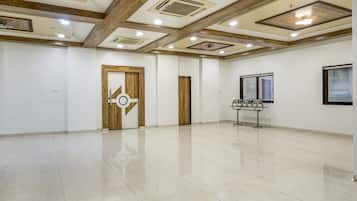 A spacious room with a polished floor, a no-smoking sign, and a window with blinds.