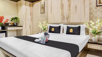 A hotel room with a bed, a bedside table, a nightstand, a mirror, and a wall-mounted picture.