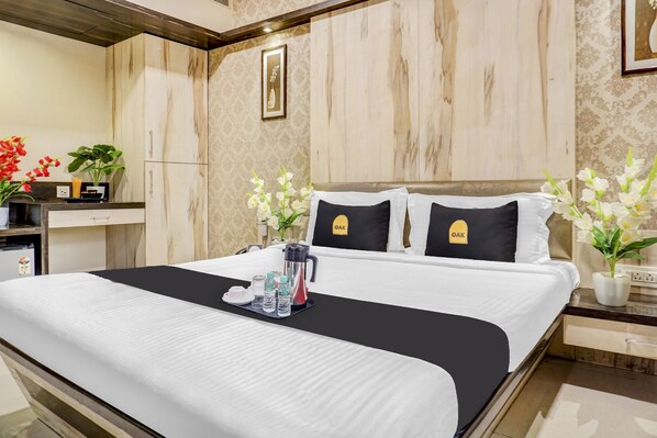 A hotel room with a bed, a bedside table, a nightstand, a mirror, and a wall-mounted picture.