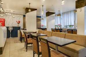 Un interior de restaurante con mesas, sofás y un ventilador cerca de la entrada.