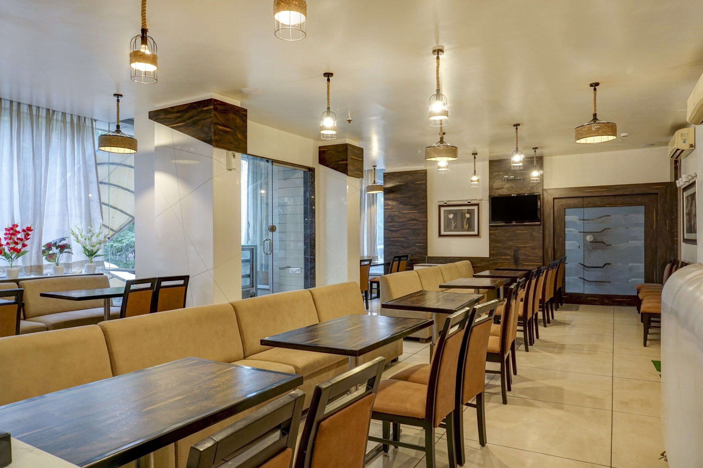 A restaurant interior with multiple seating arrangements, including booths and tables, and a large wall-mounted television.