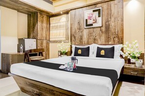 A hotel room with a wooden headboard, a bed with white bedding, a nightstand with a lamp, a chair, and a picture on the wall.