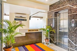 A reception area with a marble wall, a reception desk, and an elevator.