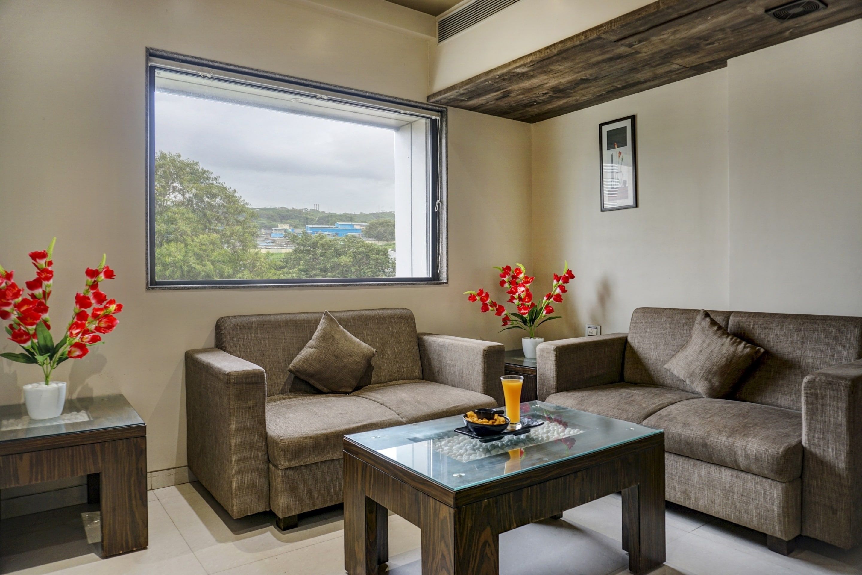 A living room with two sofas, a glass coffee table, and a window with a view of buildings and trees.
