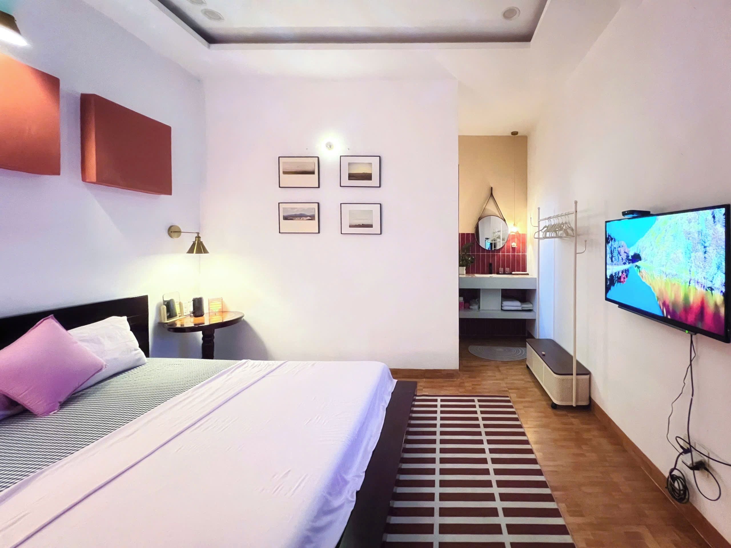 Een hotelkamer met een bed, een televisie, een bureau en een badkamer op de achtergrond.