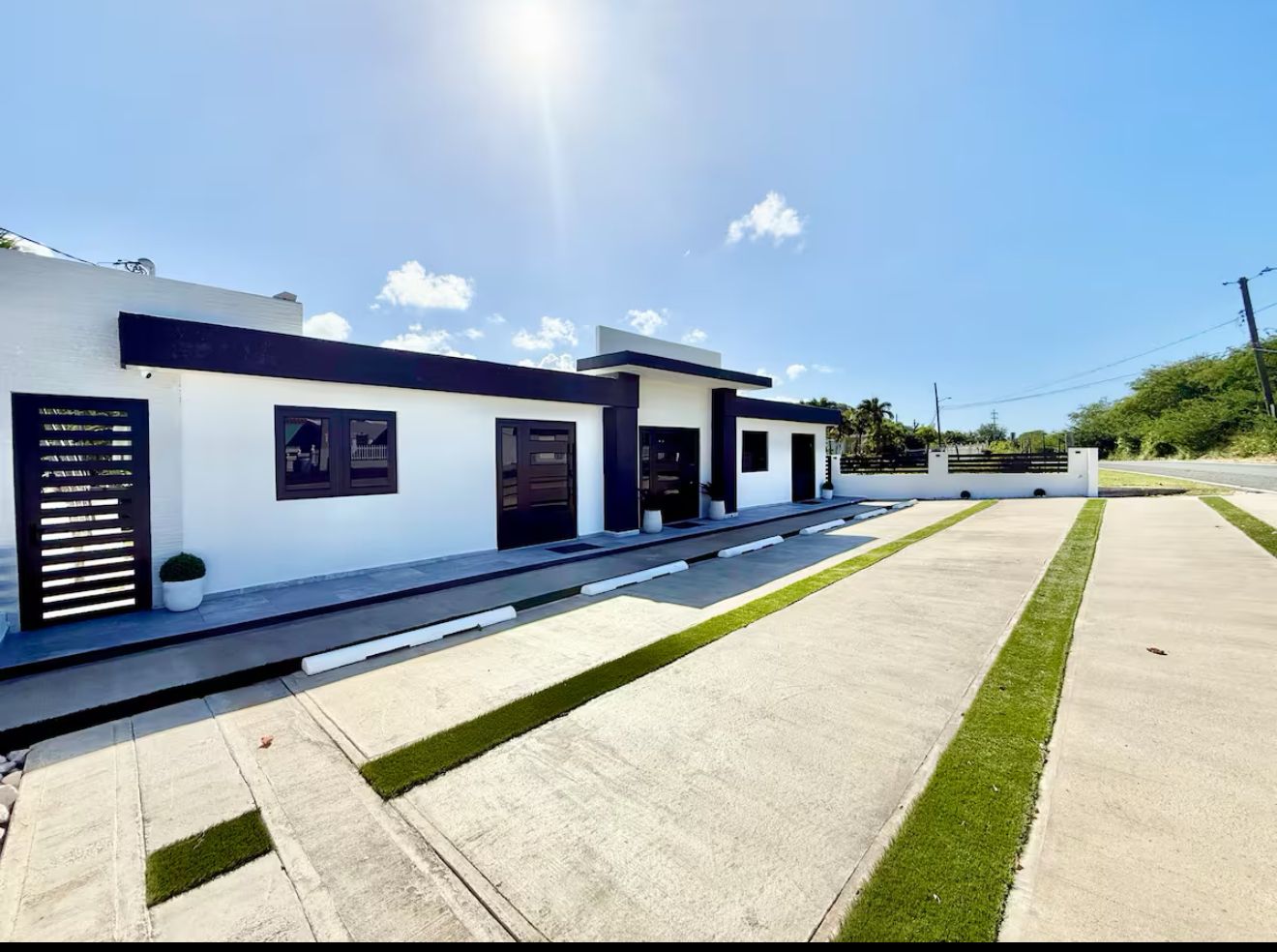 A modern building with a flat roof, a concrete driveway, and a well-maintained lawn.
