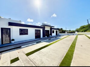 Un bâtiment moderne doté d’un toit plat, d’une allée en béton et d’une pelouse bien entretenue.