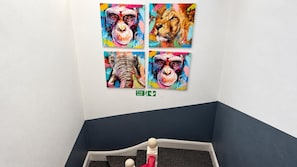 A corner of a room with a white wall and a dark blue accent wall. There are four colorful paintings of animals on the wall. - Ensuite Studio, Sleeps 4 With Wifi (London)
