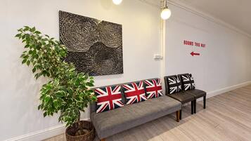 A waiting area with a bench, a wall-mounted artwork, a potted plant, and a directional sign.