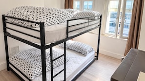A bunk bed with patterned bedding in a room with a window and a desk. - Ensuite Studio, Sleeps 4 With Wifi (London)