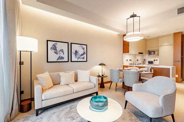 A modern living room with a sofa, armchairs, a coffee table, and artwork on the wall. - Luxury 1BR in Address Opera, Close to Dubai Mall (Dubai)