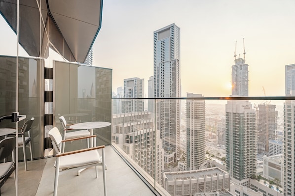 A balcony with a glass partition, a round table, and two chairs. - Luxury 1BR in Address Opera, Close to Dubai Mall (Dubai)