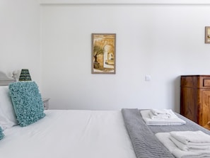 Ein Schlafzimmer mit einem Bett, einem Bild, einer Lampe und einem Nachttisch.