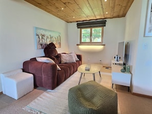 Ein Wohnzimmer mit einer Couch, einem Couchtisch, einer TV-Konsole und einem Gemälde an der Wand.