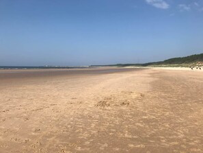 Ein weiter Sandstrand unter einem klaren Himmel.