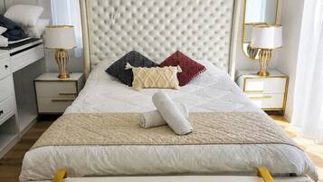 A neatly made bed with a tufted headboard, bedside tables with lamps, and a bench.