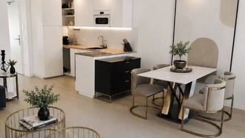 A modern, compact living space with a kitchenette, a dining area with a table and chairs, and a seating area with a sofa and coffee table.
