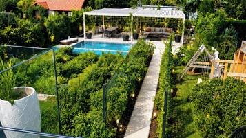 A rooftop garden with a swimming pool, seating area, and a pergola.