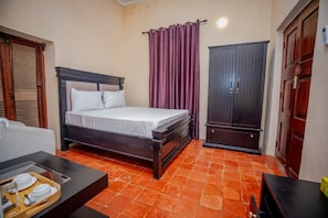 A bedroom with a bed, a wardrobe, and a small table with a tray of dishes. - Cathedral Hotel  (Zanzibar Town)